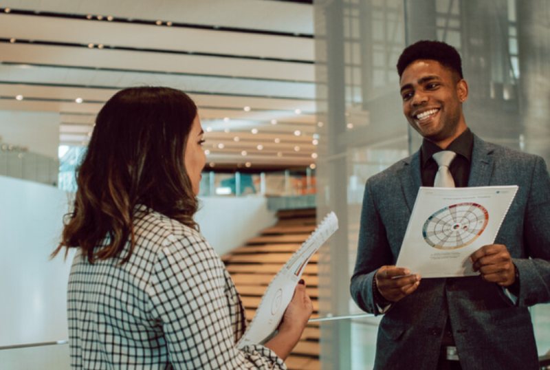 Two colleagues discussing change management strategies with a circular Insights Discovery chart in a modern office setting